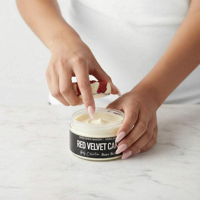 Woman with long light pink nails dipping finger into Red Velvet Cake body butter jar on marble surface