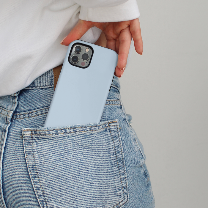 A blue Tough Phone Case by Coconut Lane being slipped into the back pocket of light blue jeans.
