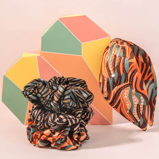 Two patterned scrunchies in front of a geometric hexagonal block on a light pink background